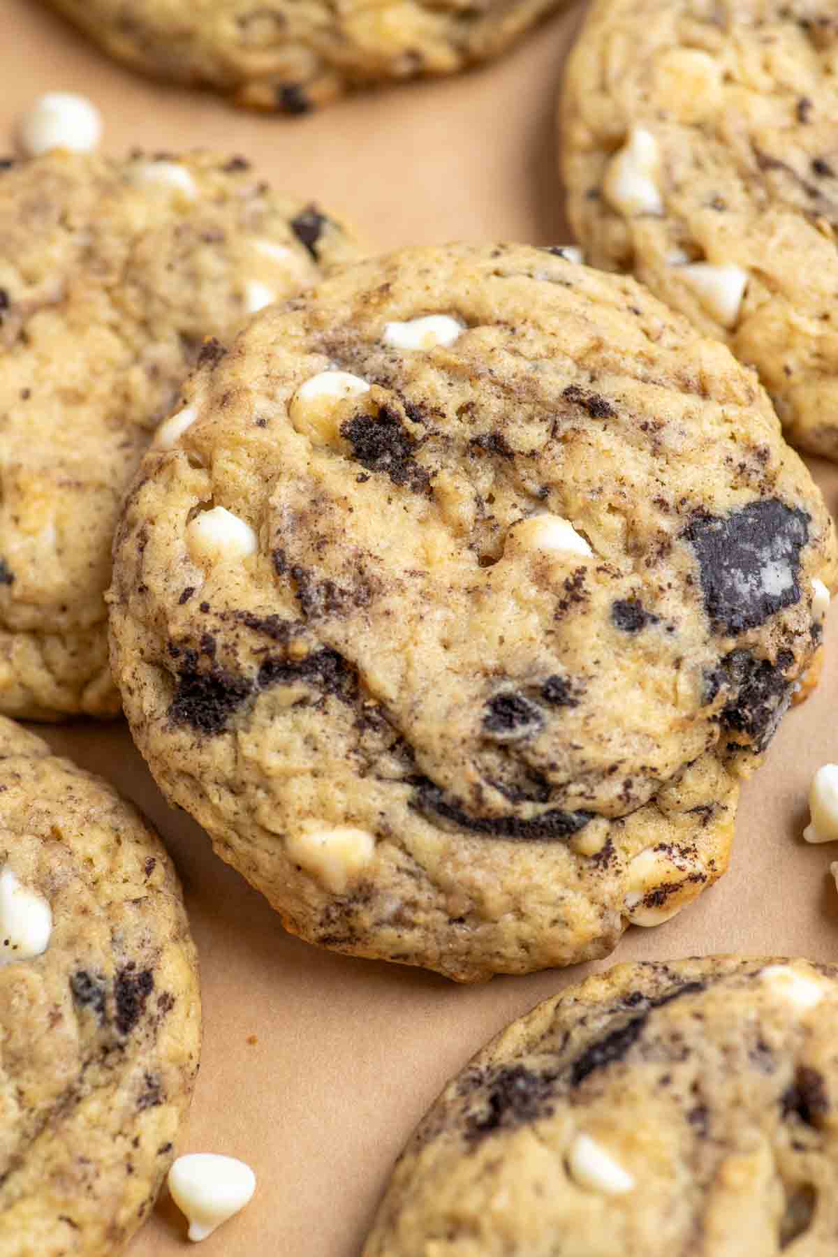 Close up picture of sourdough cookies and cream cookies with chunks of white chocolate and cookie pieces spread out on parchment paper.