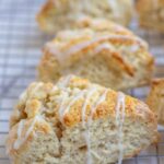 Sourdough discard lemon scones drizzled with lemon icing on a cooling rack.
