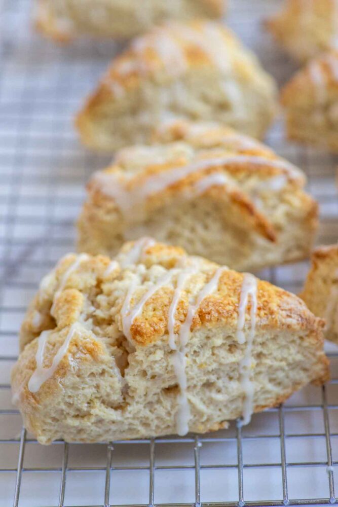 Sourdough discard lemon scones drizzled with lemon icing on a cooling rack.