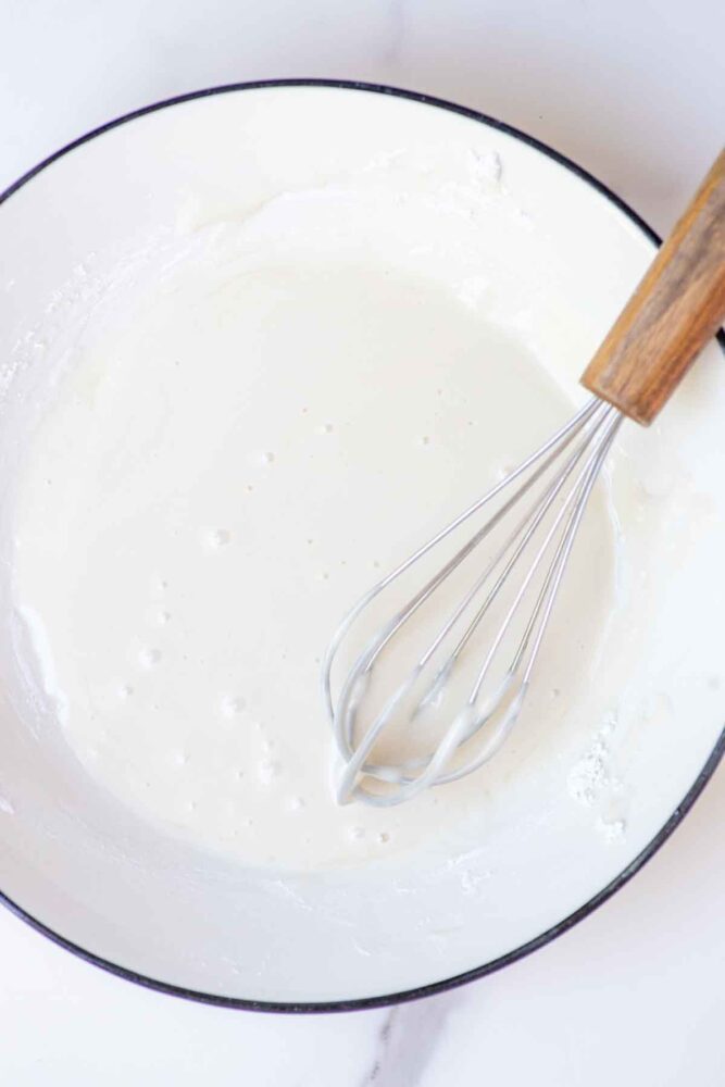 Lemon icing in a bowl with whisk.