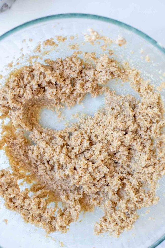 Creaming brown sugar, sugar, and butter together in a glass bowl.