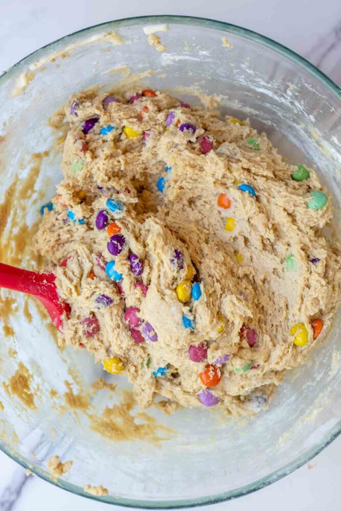 Stirring m&ms into cookie dough batter.