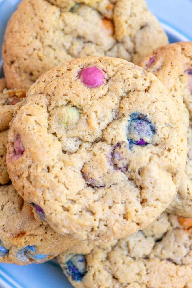 Up close picture of sourdough M&M Cookies stacked on a blue plate.