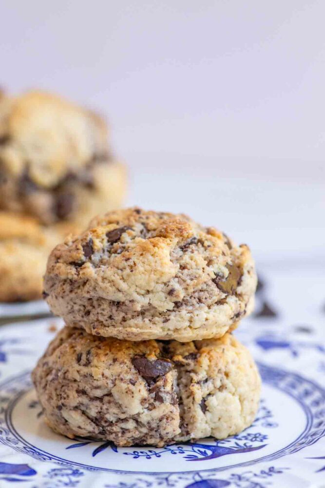 Close up photo of two sourdough chocolate chip scones stacked on blue and white vintage plate.
