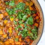 Half of a pot of sweet potato chili topped with cilantro,