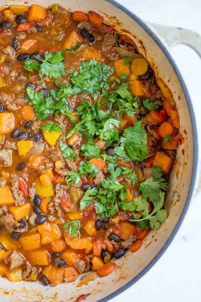 Half of a pot of sweet potato chili topped with cilantro,