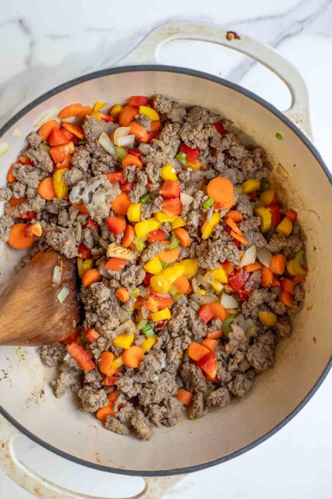 Ground beef with vegetables in a dutch oven.