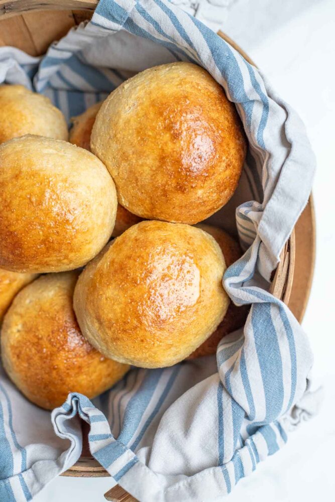 Whole wheat burger buns in a towel lined basket.