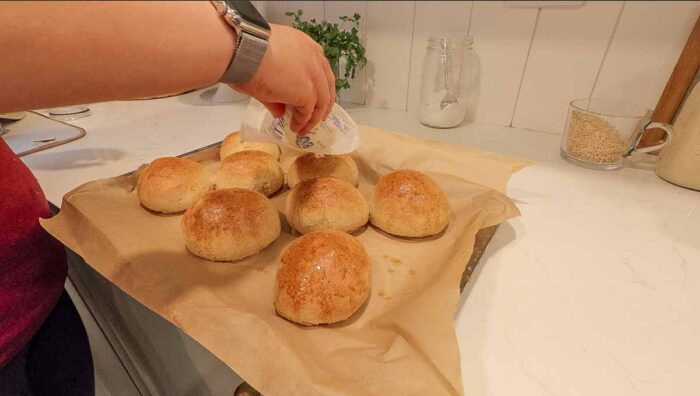 adding butter to the top of whole wheat burger buns.